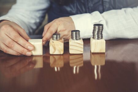 woman hand coins on wooden cubes on tableの写真素材