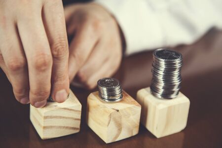 woman hand coins on wooden cubes on tableの写真素材