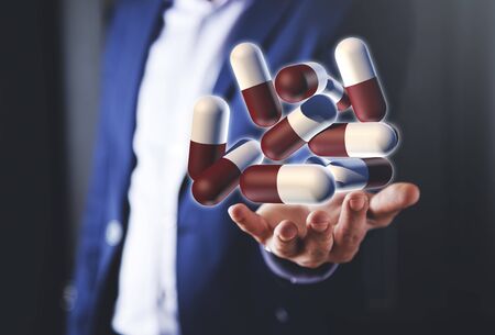 Business man holding group of medical pillsの写真素材