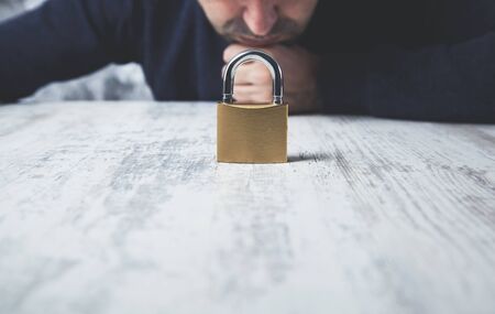 sad man hand lock on the wooden  tableの写真素材