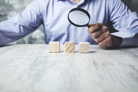 man hand magnifier with wooden cubes on deskの写真素材