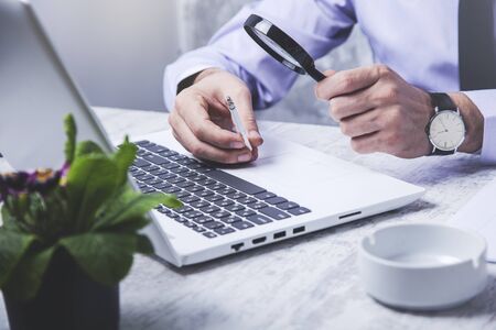 man hand magnifier with cigarettes on keyboardの写真素材