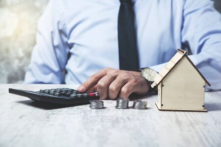 man hand coins with calculator and house modelの写真素材