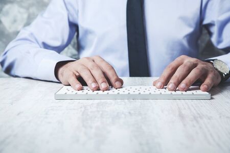 business man hand holding computer keyboard on deskの写真素材