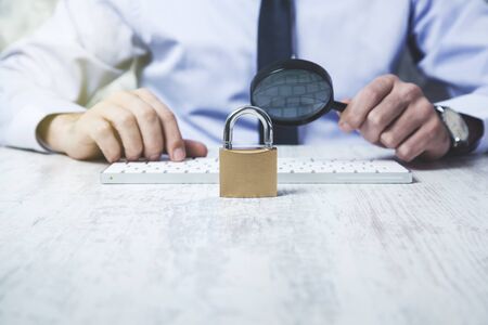business man hand magnifier and lock with keyboard