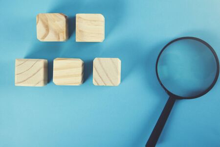 wooden cubes with magnifier on the blue backgroundの写真素材