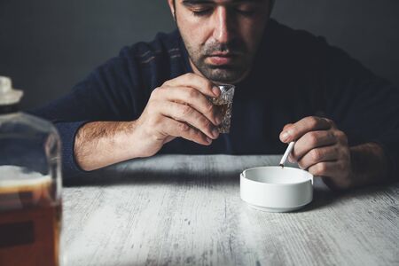 sad man hand  whiskey with cigarettes on deskの写真素材