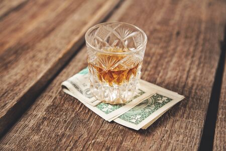 whiskey glass on money onthe wooden deskの写真素材