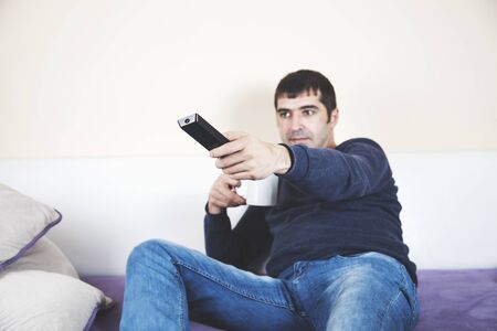 man hand remote control sitting  on sofaの写真素材