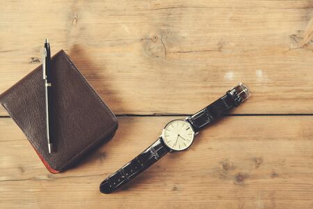 watch with pen and wallet on deskの写真素材