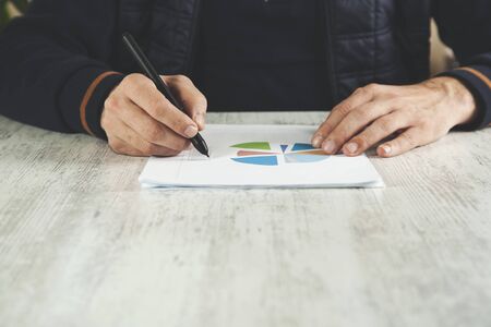 man hand pen with graph on the desk
