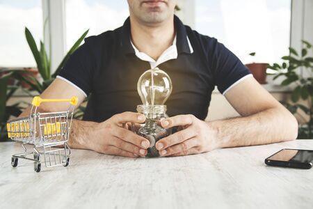 man hand light bulb with coins on deskの写真素材