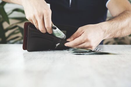 man hnad money with wallet on desk