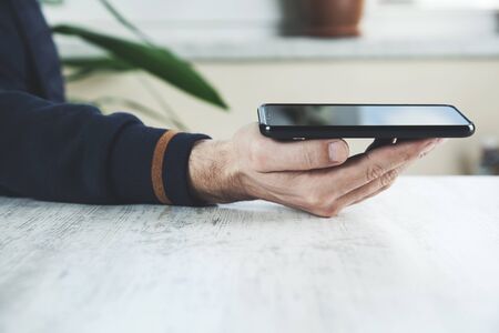 man hand holding phone on the tableの写真素材