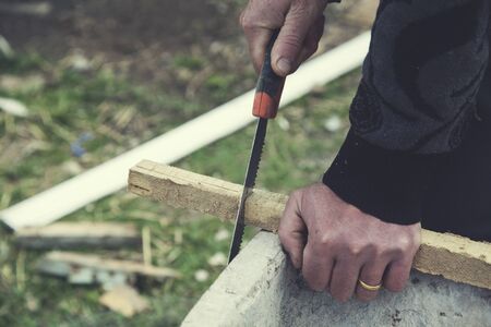 man hand saws with wood in natureの写真素材