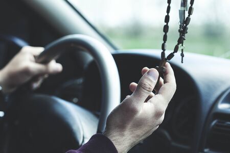 man hand holding cross  necklace in car