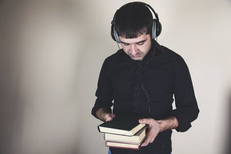 young man hand holding earphone with booksの写真素材