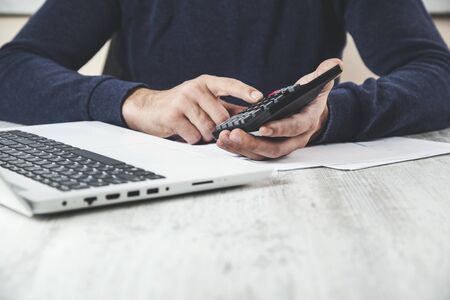 man hand calculator with document and computer on desk