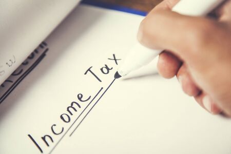 man written income tax text on paperの写真素材