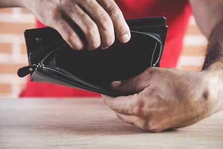 young man hand holding black wallet on desk