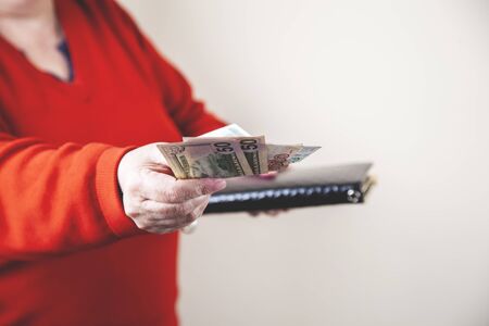 woman hand wallet and money on grey background