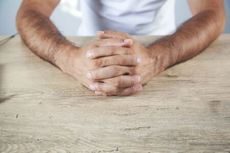 man cross fingers on the wooden deskの写真素材