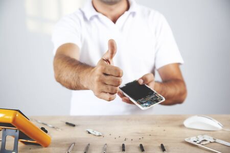 worker hand phone with tester on working wooden deskの写真素材