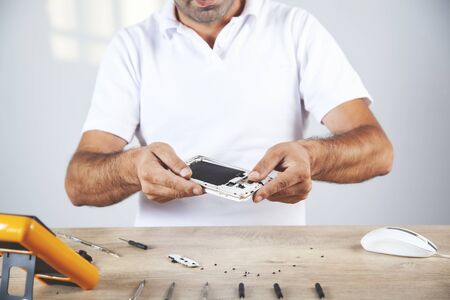 worker hand phone with tester on working wooden deskの写真素材