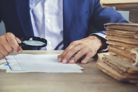 man hand magnifier and document on the deskの写真素材