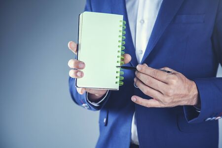 business man hand holding empty notepad on gray backgroundの写真素材
