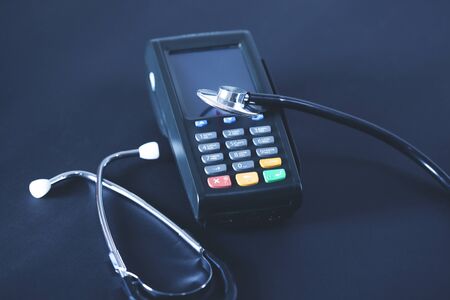 stethoscope on payment device on the dark backgroundの写真素材