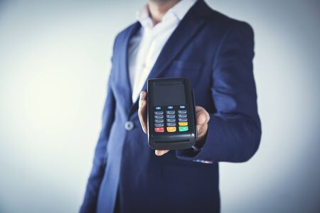 man hand holding paymant terminal on gray backgroundの写真素材