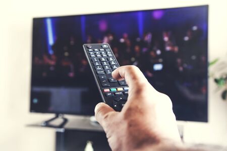 man hand remote control with TV background