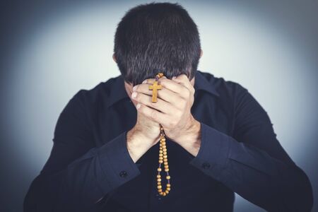 Prayer man hand cross on the gray wll background