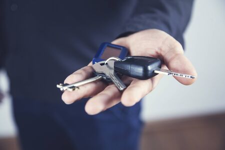 man hand car key on the gray wall background