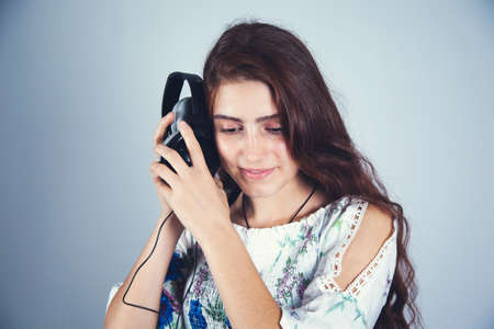young woman hand earphone on gray background