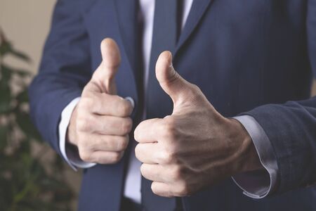 young business man hand okay sign in office background