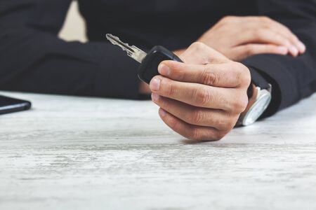 Hands of man holding the car keys on wooden tableの写真素材