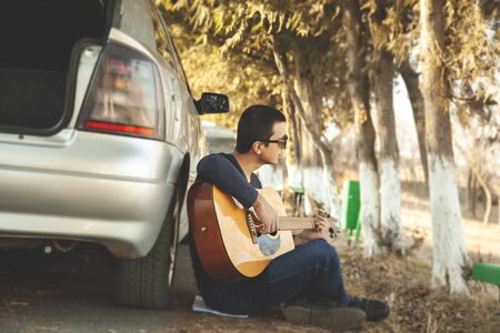 Young man plays beautiful music in natureの写真素材