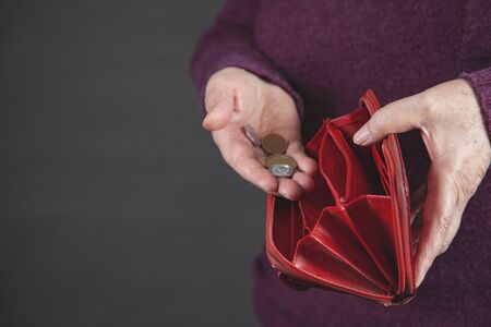 The old woman holding coin on grey background