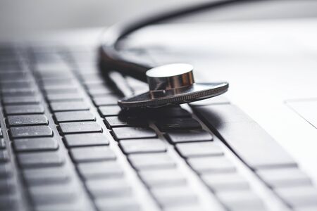 Stethoscope on the black keyboard of laptop computerの写真素材