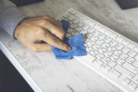 Cleaning the surface of keyboard laptop with a blue rag microfiber