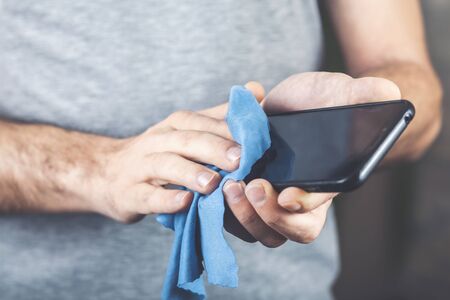 Man cleaning cell phone. Health prevention by virus. Coronavirus. Covid-19の写真素材