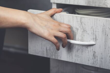 Woman hand pulling open wooden drawer in officeの写真素材