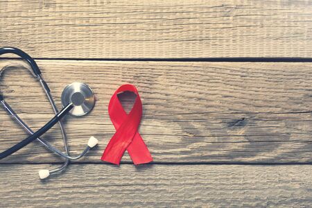 red ribbon and stethoscope on wooden background