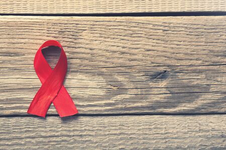 red ribbon on the wooden background AIDSの写真素材