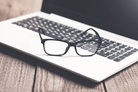 glasses on computer keyboard on wooden table