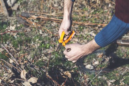 young man with pliers cuts wire in natureの写真素材