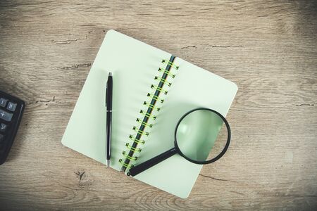 magnfier with notepad on the wooden deskの写真素材