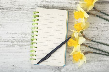 Empty sketchbook on wooden desk with orchid flowers around. Mockup for elegant design.の写真素材